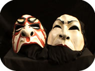 Two masks lying on black cloth.